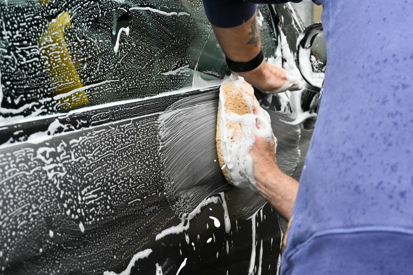 Hand washing a car with a sponge